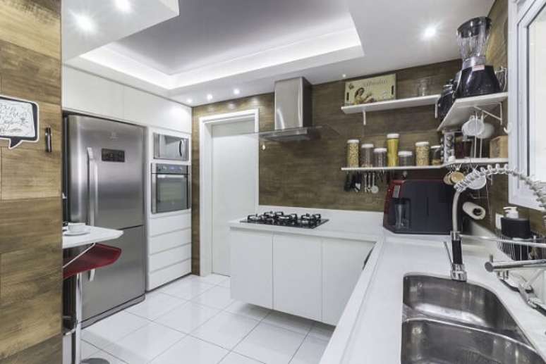 8. Os armários desta cozinha modulada são brancos e o destaque ficam por conta das paredes com revestimento de madeira. Projeto de Andre Freitas