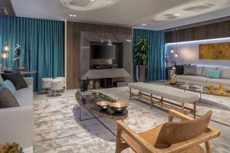 42. Sala de TV ampla com m&oacute;veis cinzas e cortina turquesa. Projeto de Casa Cor Bras&iacute;lia 17