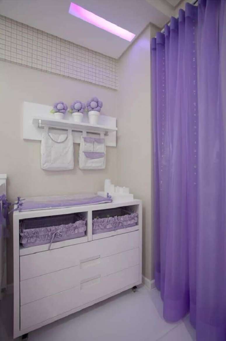 15. Decoração para quarto de bebê feminino em tons de branco e lilás na cômoda com trocador