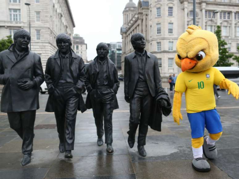 Canarinho com a estátua dos Beatles, em Liverpool, Inglaterra; orientação é de que mascote explore monumentos