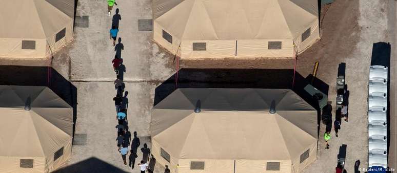 Menores são conduzidos em fila indiana entre tendas de abrigo no Texas, próximo à fronteira mexicana