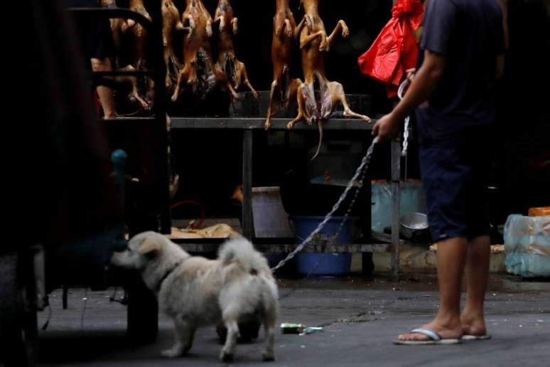 Homem com seu cachorro passa em frente a estabelecimento vendendo carne de cachorro em cidade chinesa de Yulin 21/06/2018 REUTERS/Tyrone Siu