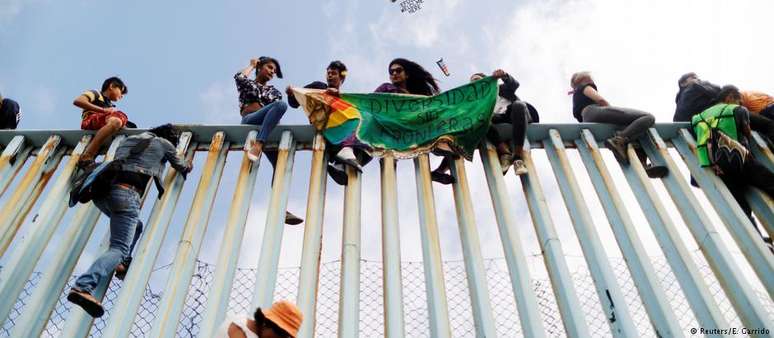 Com faixa que diz "diversidade sem fronteiras", cidadãos da América Central protestam em cerca entre EUA e México