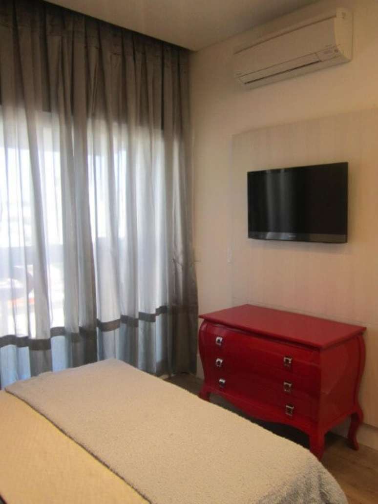 16. Uma c&ocirc;moda retr&ocirc; vermelha baixa no quarto de casal. Projeto de Sueli Porwjan