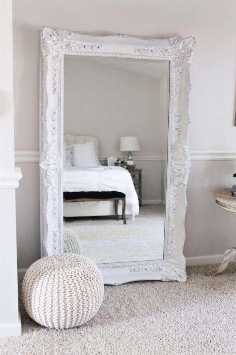 1. Espelho grande para quarto com moldura branca e clássica deixando a decoração mais sofisticada e delicada.