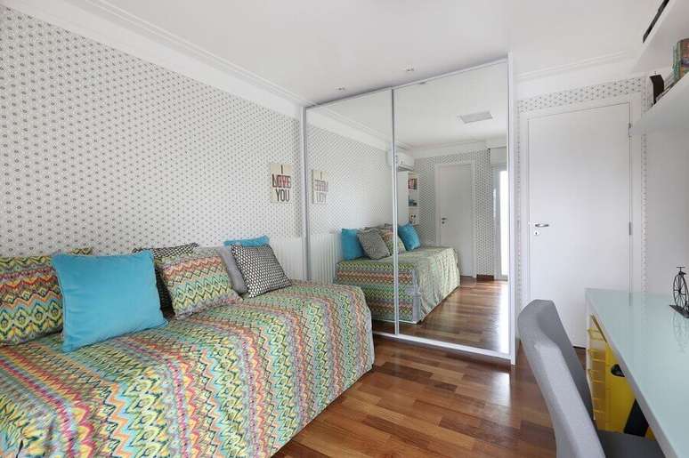 4. O toque divertido de cor na decora&ccedil;&atilde;o deste quarto com guarda roupa solteiro com espelho ficou por conta das almofadas e roupa de cama
