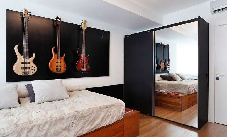 50. Quarto de solteiro com decora&ccedil;&atilde;o simples com guitarras na parede e guarda roupa solteiro porta de correr espelhada