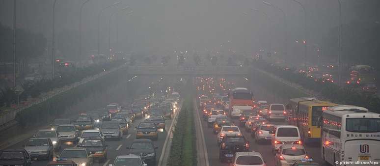 Avenida em Pequim com trânsito intenso e nuvem escura de poluição