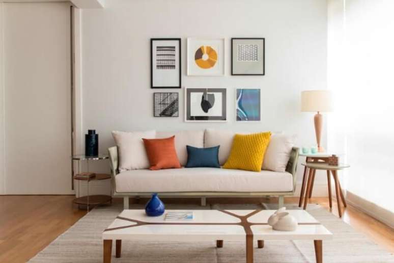 25. Sala de estar com mesas laterais redondas de designs diferentes aos lados do sofá. Projeto de Marilia Veiga