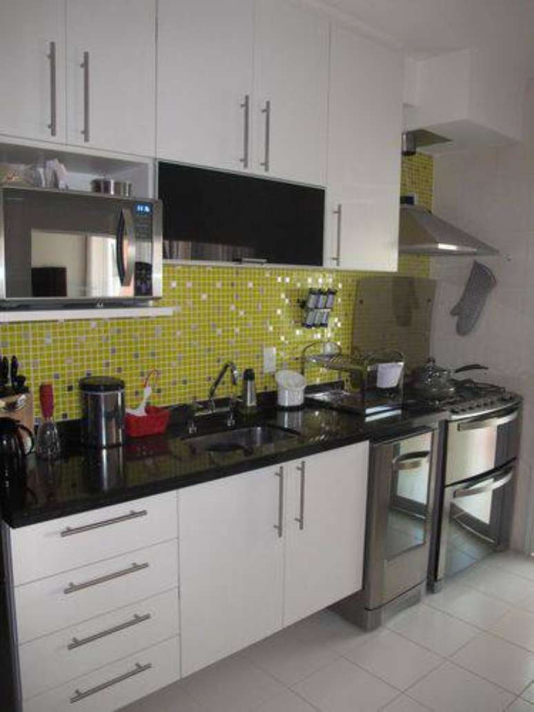 13. Cozinha pequena com pastilhas amarelas, armários brancos e bancada de granito preto absoluto. Projeto de Mariane Battaglia