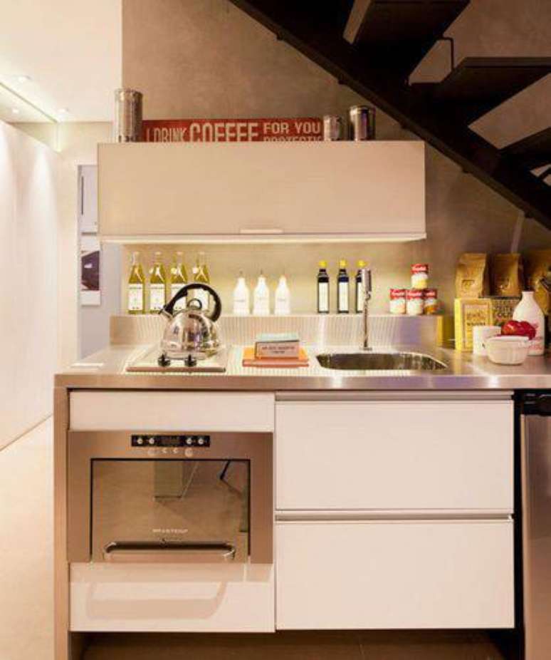 27. Esta cozinha compacta embaixo da escada otimiza o pouco espaço com móveis planejados. Projeto de Basiches Arquitetos