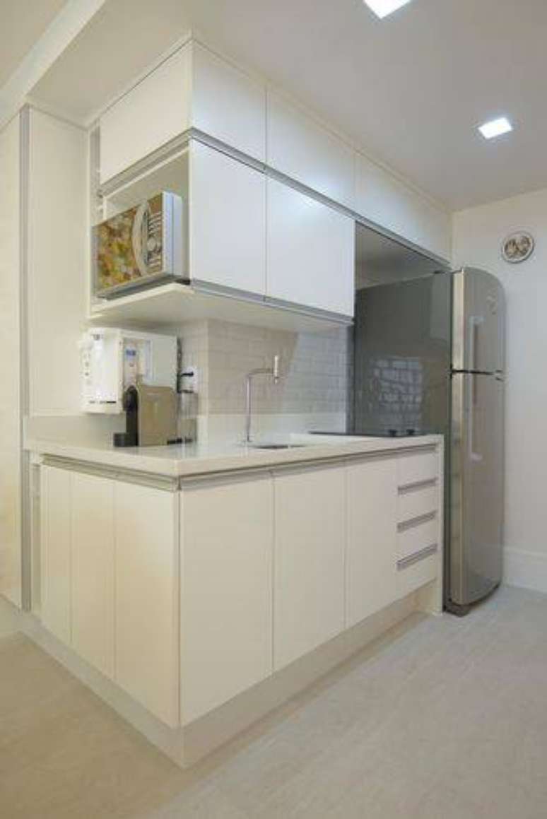 12. Cozinha compacta com armários planejados brancos e parte do revestimento de azulejo metro white. Projeto de Ravaglia Philot
