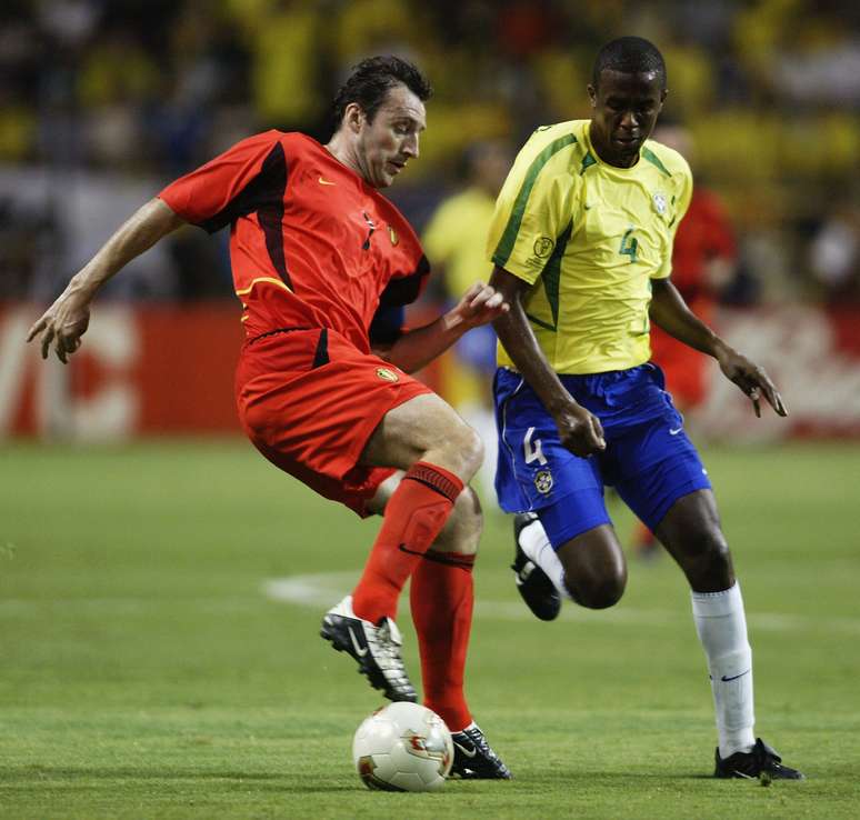 O então atacante Marc Wilmots tenta passar pelo brasileiro Roque Júnior, na Copa de 2002