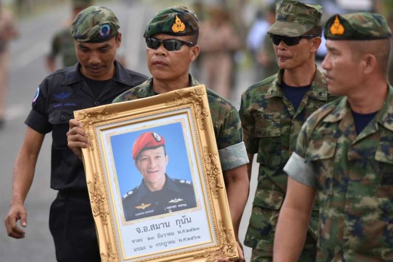 Militares tailandeses carregam quadro com fotografia de Samarn Poonan, ex-mergulhador de elite, morto nos esforços para resgatar um grupo de meninos e seu técnico presos numa caverna
06/07/2018
REUTERS/Panumas Sanguanwong