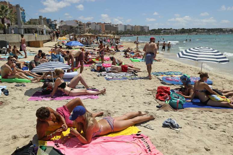 Turistas relaxam na praia em Palma, Maiorca, em trecho popular de festas 