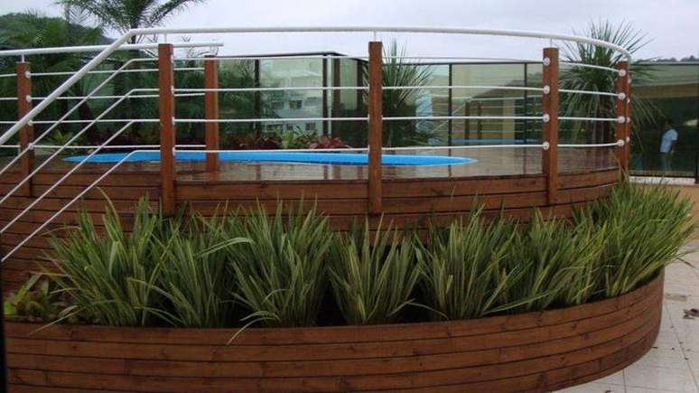 17. Plantas de jardim em torno do deck de madeira deixa o ambiente da piscina de fibra mais aconchegante