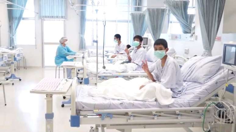 Captura de tela mostra meninos resgatados de caverna na Tailândia usando máscaras em hospital em Chiang Rai