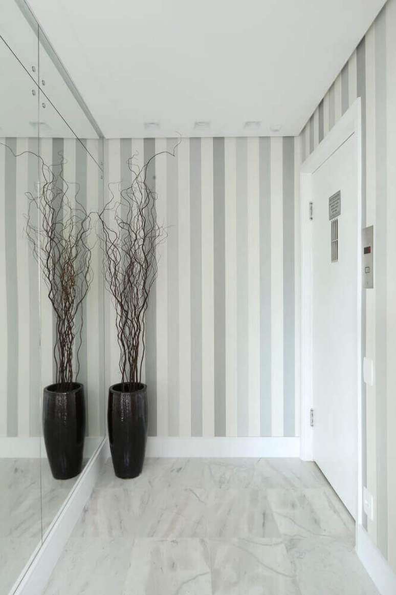 26. Decora&ccedil;&atilde;o para hall em tons de cinza e branco com papel de parede listrado e vaso preto grande