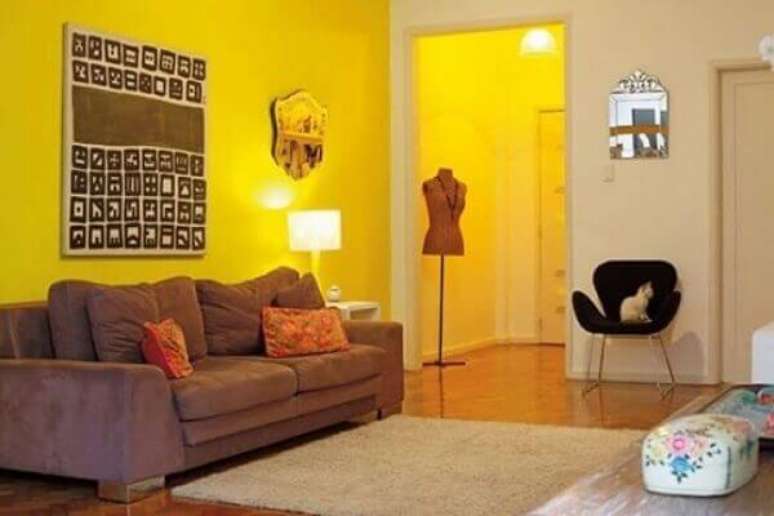 21- As cores de parede para sala amarela combinam perfeitamente com móveis escuros.