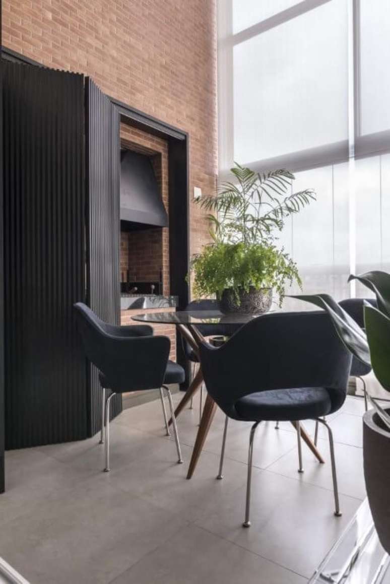 44. Mesa com base de madeira e cadeiras estofadas pretas. Projeto de Mauricio Karam