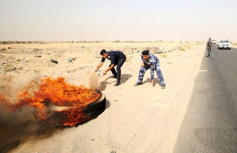 Policiais iraquianos tentam apagar fogo em pneu durante protesto na entrada principal do campo de petróleo de Zubair 17/07/2018 REUTERS/Essam al-Sudani