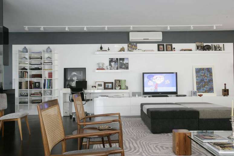 37. O projeto da AMC Arquitetura integra sala de estar e home office com estante para TV e livros.