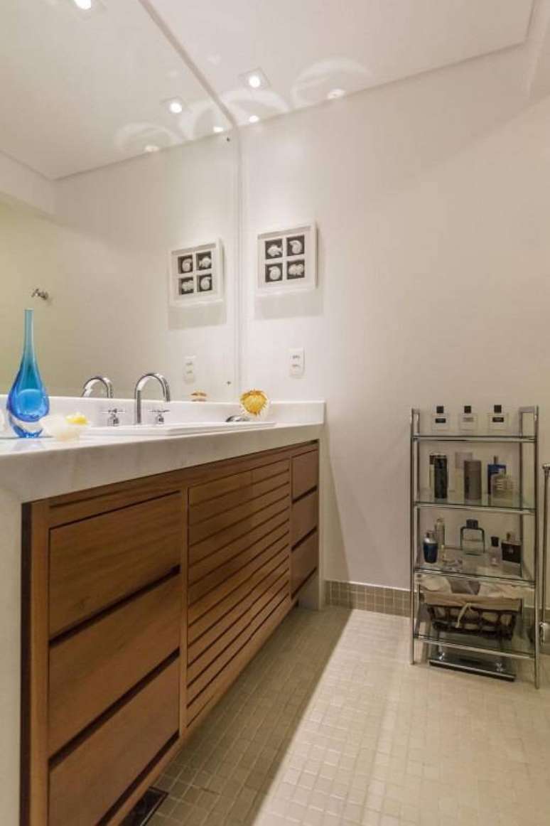 47. No banheiro, a estante baixa de metal e vidro pode organizar perfumes e cosm&eacute;ticos. Projeto por Fernanda Duarte.