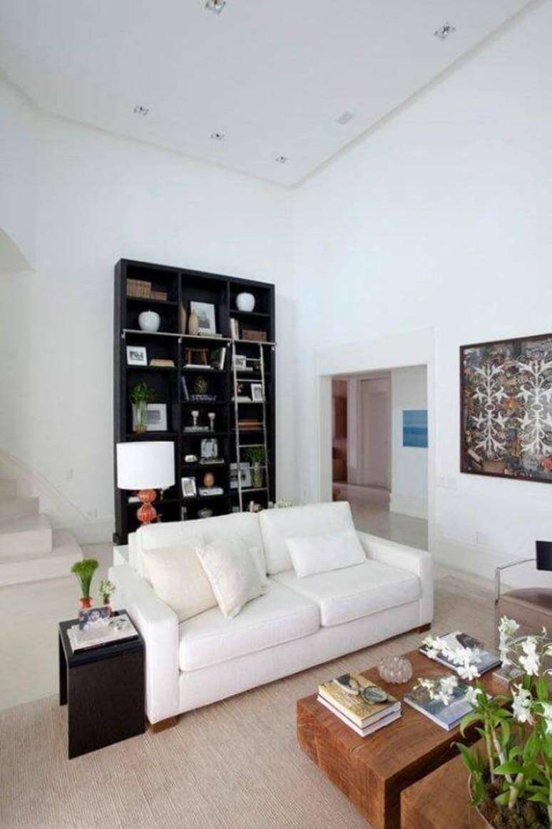 54. A estante preta com escada aproveita a parede da passagem atr&aacute;s do sof&aacute;. Projeto por Dado Castello Branco.