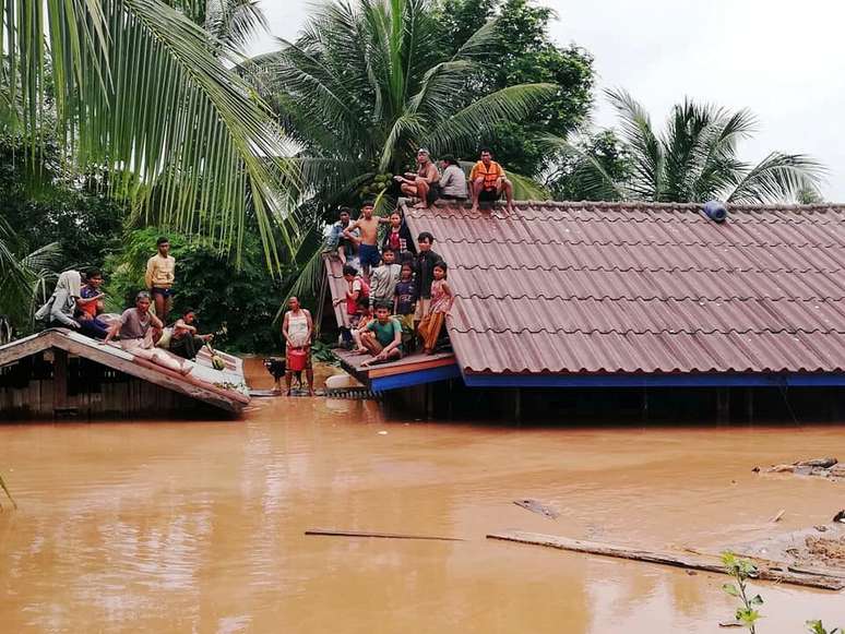Moradores sobem nos telhados das casas após rompimento de barragem de hidrelétrica no Laos 24/07/2018