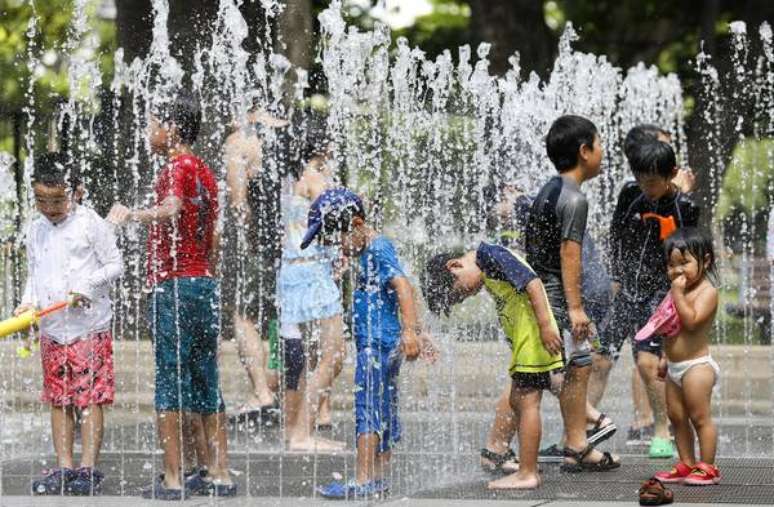 Crianças brincam na água graças às ondas de calor que trouxeram temperaturas superiores a 41.1º C, no Japão.