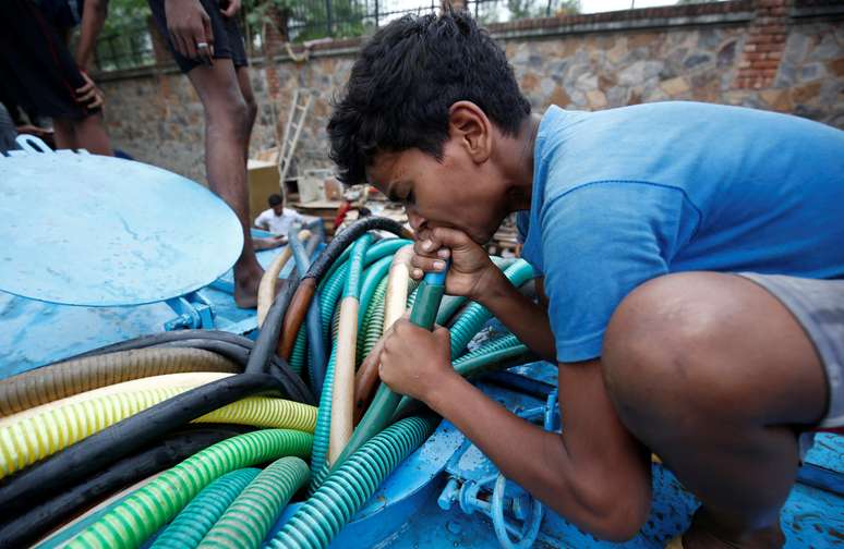Menino puxa água de tanque em Nova Delhi, cidade que já enfrentou inclusive falta de água neste ano