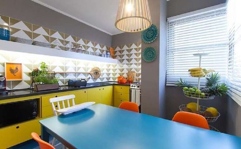 15. Decoração com armário de cozinha retrô pintado de amarelo e mesa azul – Foto: Mauricio Arruda