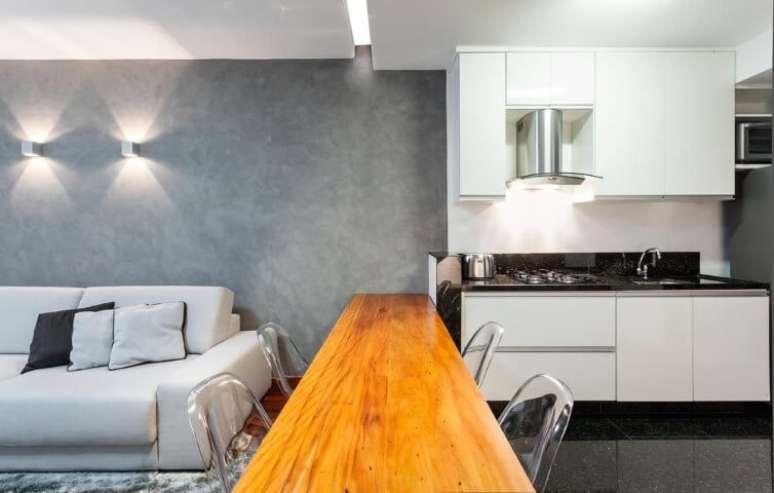 26. Aqui, a cozinha e a sala são ligadas por uma mesa de madeira. Projeto de Laura Santos