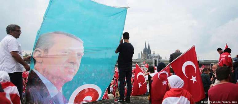 Adeptos de Erdogan portam sua efígie e bandeiras da Turquia, com a catedral de Colônia ao fundo