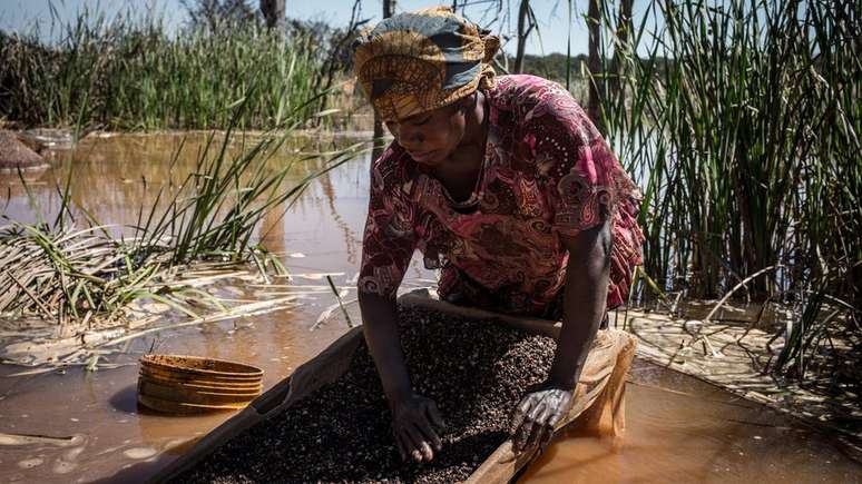 Mulher separa cobalto de lama e pedras perto de uma mina na República Democrática do Congo