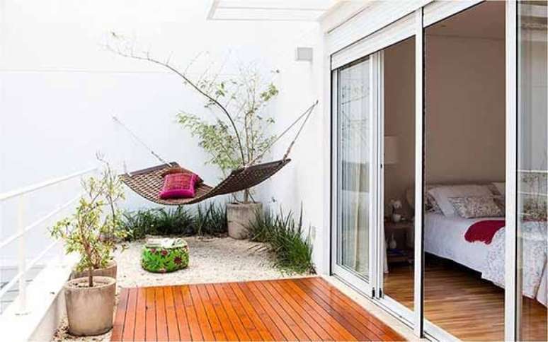 16- A varanda decorada com deck e rede em fibra natural ganha um elemento alto com o bambu moss&ocirc; que complementam essa decora&ccedil;&atilde;o. Fonte: Ello Construtora