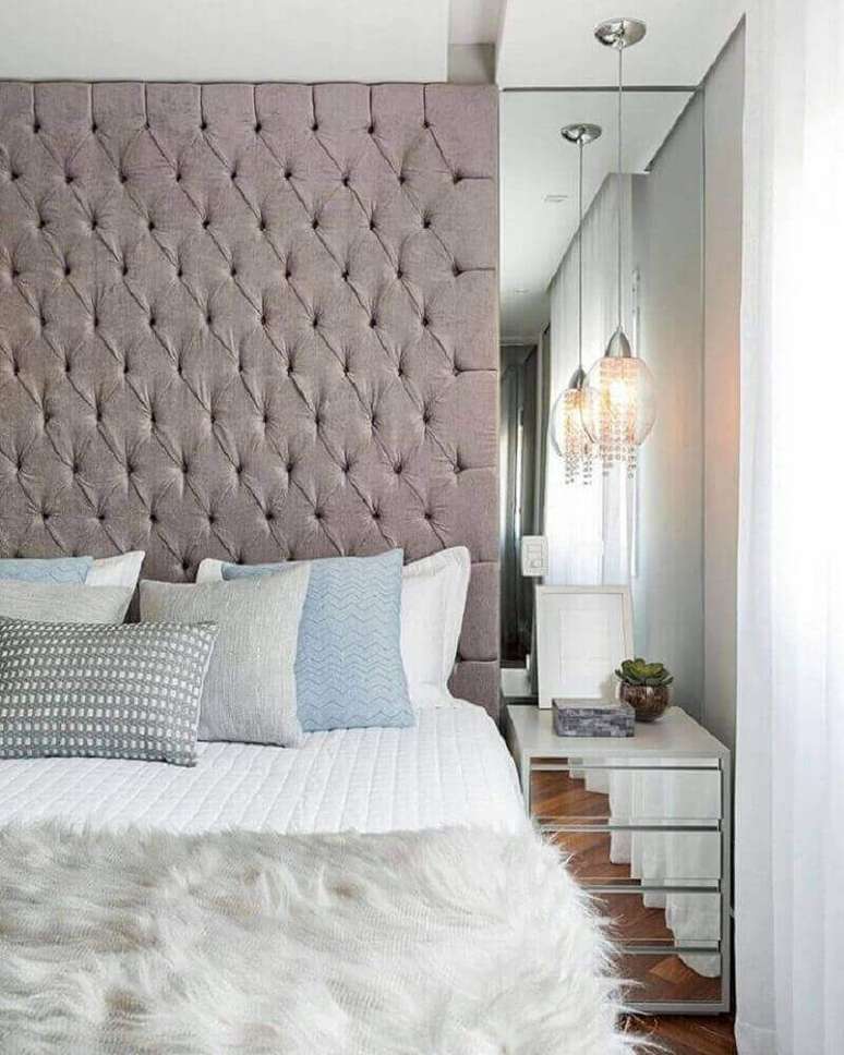 22. Modelo de cabeceira capitonê cinza para quarto com parede e criado-mudo espelhado – Foto: Viva Decora