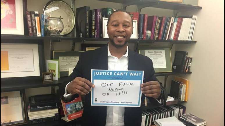 Jarrett Adams segura um cartaz com a mensagem: "a justiça não pode esperar, porque nosso futuro depende dela".