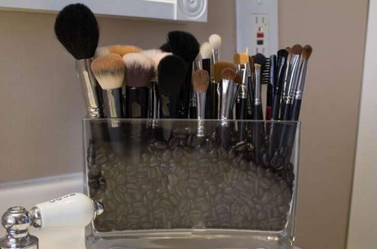 70- Caixa de acr&iacute;lico com gr&atilde;os de caf&eacute; para fixar os pinc&eacute;is de maquiagem. Fonte: Dicas de Mulher