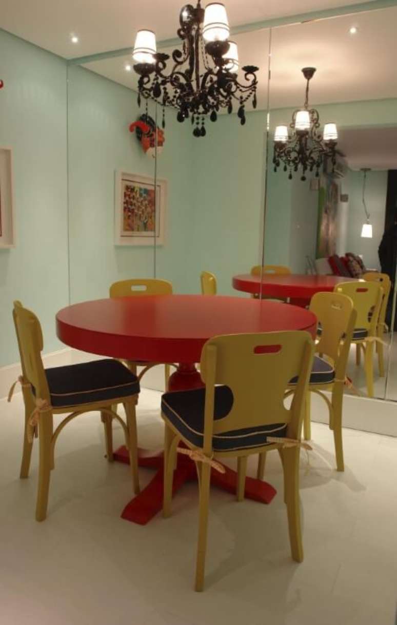 16. Mesa de jantar redonda e vermelha com cadeiras amarelas. Projeto de Luiz Humberto de Albuquerque