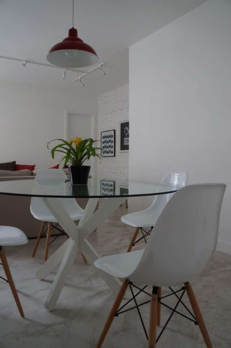 47. Sala com mesa redonda de vidro e cadeiras Eames brancas. Projeto de P Martino
