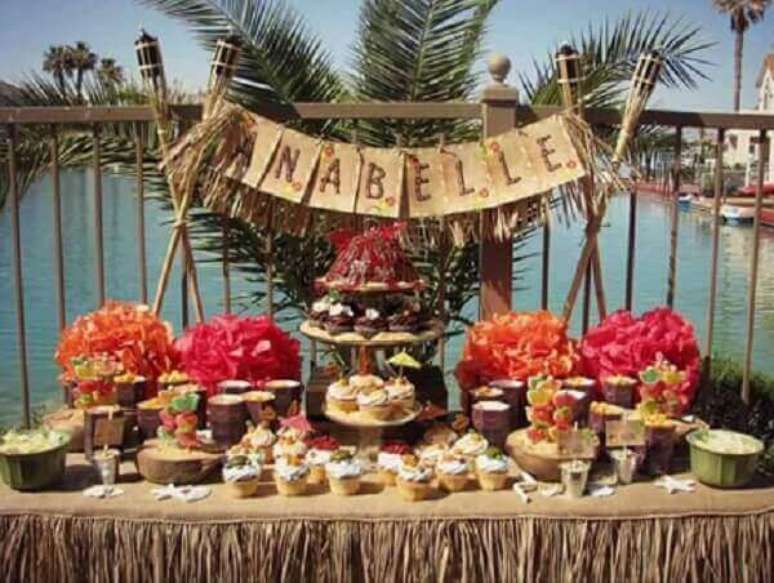 66- Mesa rústica com doces e flores deixam o ambiente tropical para festa havaiana. Fonte: Pinterest