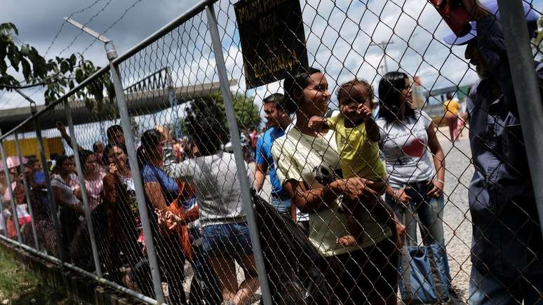 Imigrantes venezuelanos fazem fila para apresentar passaporte e entrar no Brasil.