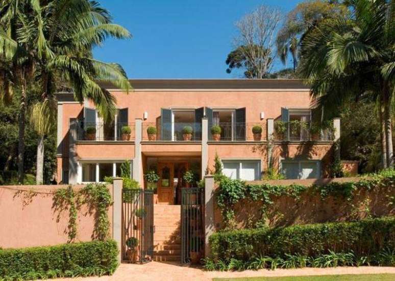 70. Modelo de casa com muita vegeta&ccedil;&atilde;o e com a cor salm&atilde;o predominante