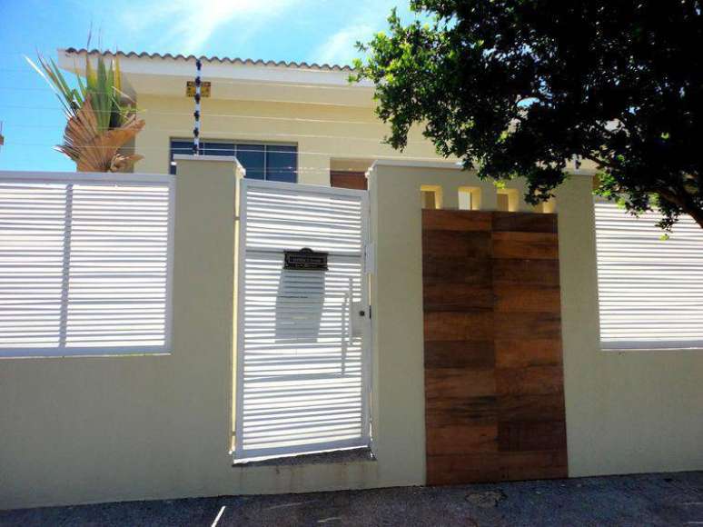 80. Fachada de casa discreta com muros e port&atilde;o de madeira