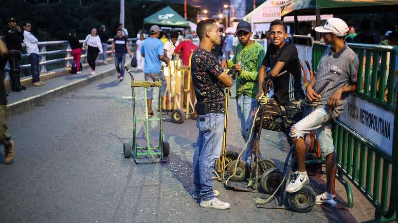 Muitos venezuelanos cruzam a fronteira durante o dia, para ganhar dinheiro fazendo bicos, e retornam de noite ao pa&iacute;s. Esse grupo de jovens ganha trocados carregando as malas de quem cruza a ponte