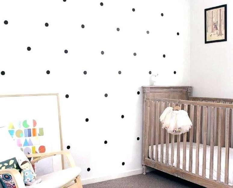 44. Decoração de quarto de bebê simples e barato com berço de madeira e papel de parede com estampa de bolinhas pretas – Foto: Pinterest
