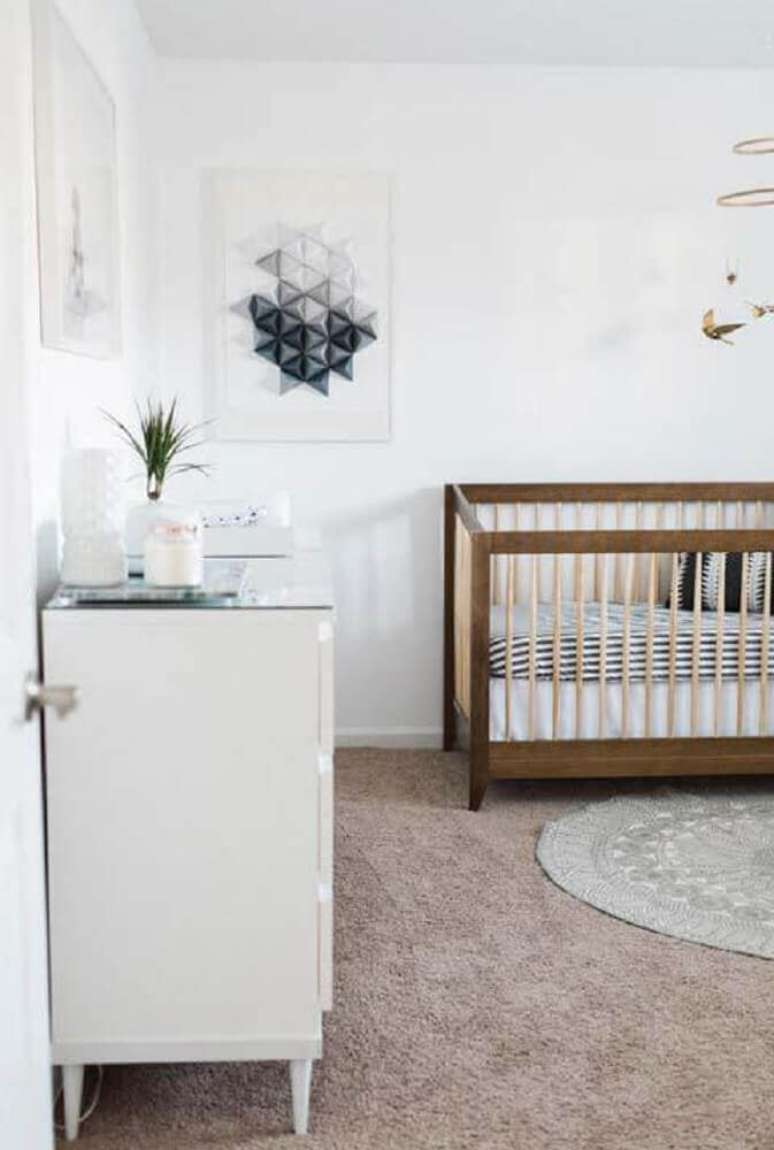 47. Aqui o minimalismo está presente tanto nos quadros quanto no berço de madeira e no tapete redondo para quarto de bebê simples e moderno – Foto: Home Decoo