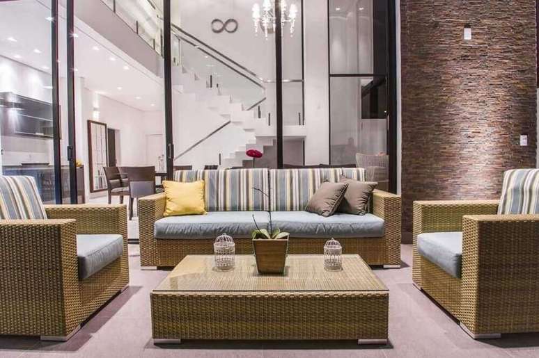 29. Decora&ccedil;&atilde;o sofisticada para sala com m&oacute;veis em vime e almofadas listradas e parede revestida de pedras &ndash; Foto: Haus Arquitetura