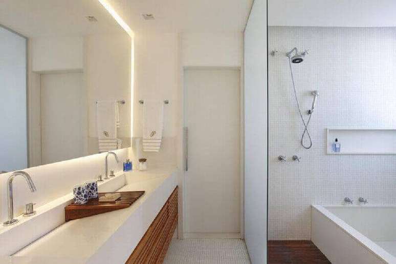 26. Banheiro branco decorado com pia moldada com rampa e fita de LED em torno do espelho – Foto: Marmoraria Casa das Rochas